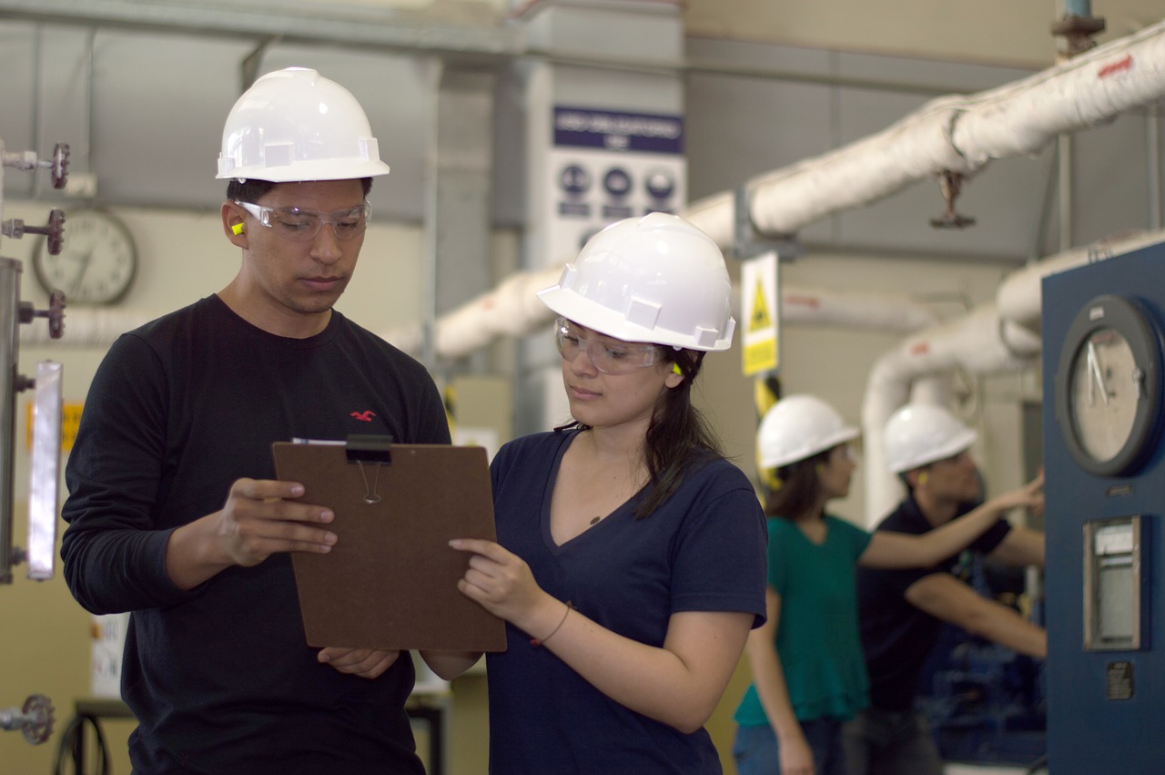 Engineers in a process manufacturing environment reviewing work on a clipboard